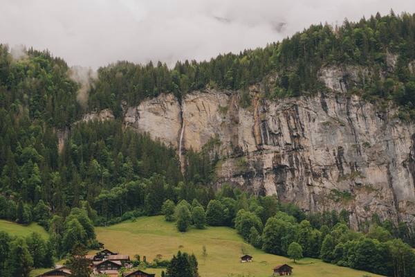 Explore the breathtaking cliffs and greenery of Lauterbrunnen, Switzerland, captured in a serene summer setting.