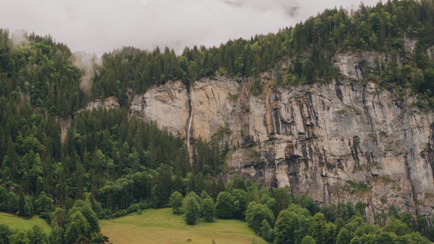 Explore the breathtaking cliffs and greenery of Lauterbrunnen, Switzerland, captured in a serene summer setting.