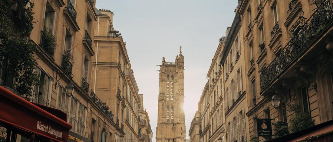 Idyllic Paris street view featuring cafés, architecture, and the historic Saint-Jacques Tower.
