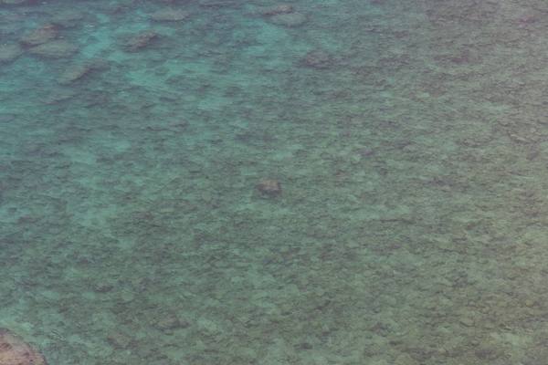A serene aerial view of turquoise waters revealing a stunning coral reef formation beneath the surface.