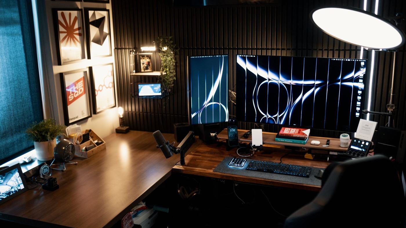 A cozy and modern home office setup featuring dual monitors, stylish decor, and ambient lighting.