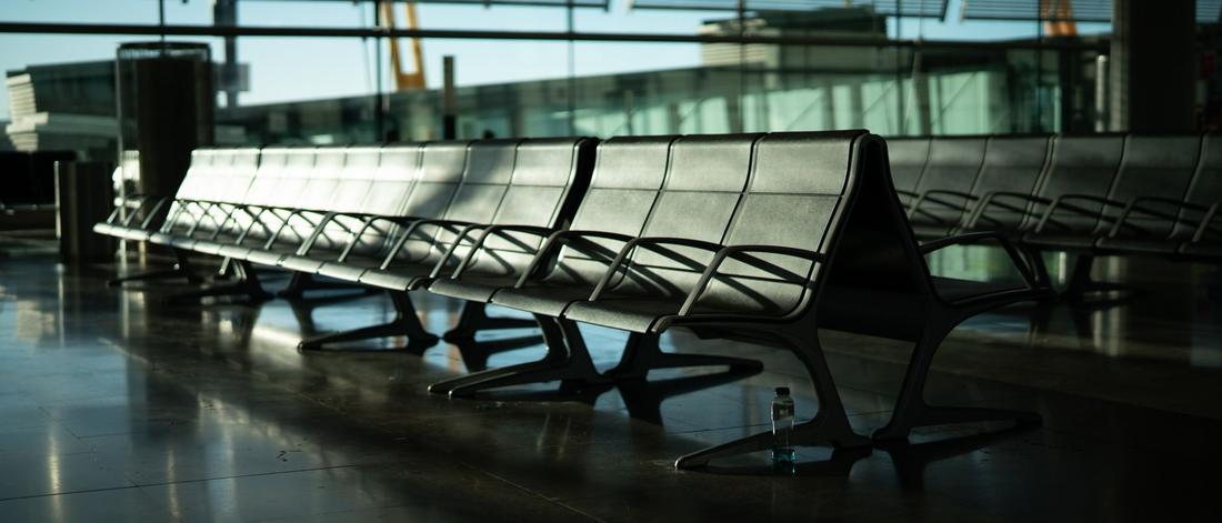 Deserted airport seating area with sunlight streaming through large windows. Calm and quiet atmosphere.