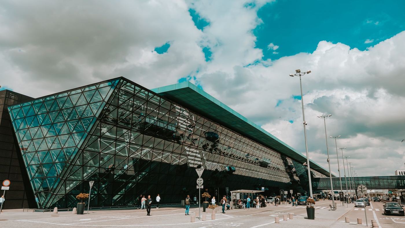 Contemporary airport terminal featuring striking glass facade under a cloudy sky.