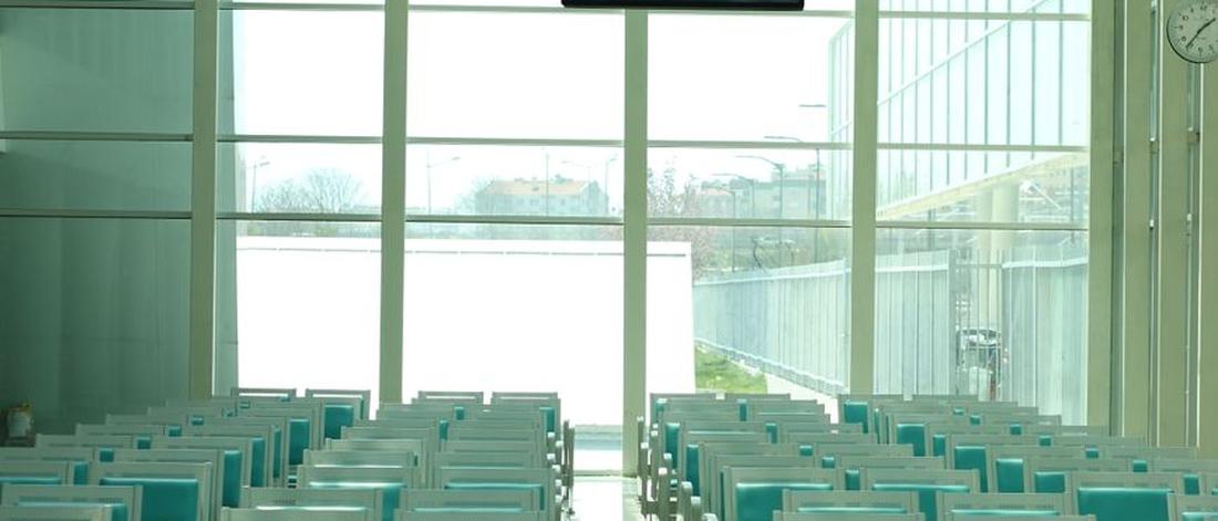 Sunlit airport waiting area with rows of teal seating and modern architecture.