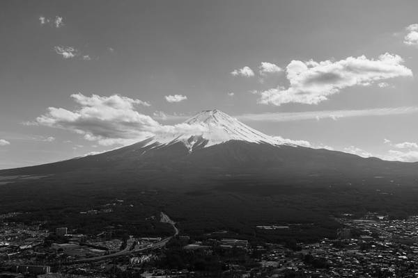 Dramatic aerial black and white capture of Mount Fuji under a clouded sky.