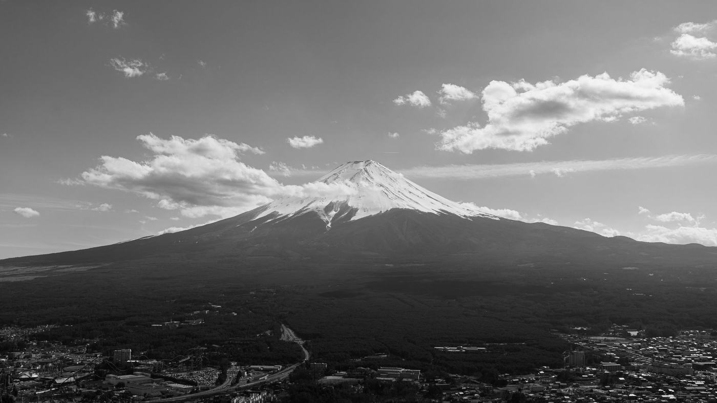 Dramatic aerial black and white capture of Mount Fuji under a clouded sky.