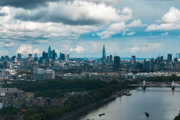 Wide-angle view of London's modern skyline and River Thames under a dramatic sky.