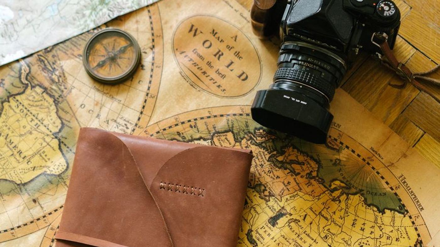 Flat lay of vintage travel items including a map, camera, and leather journal, perfect for wanderlust inspiration.