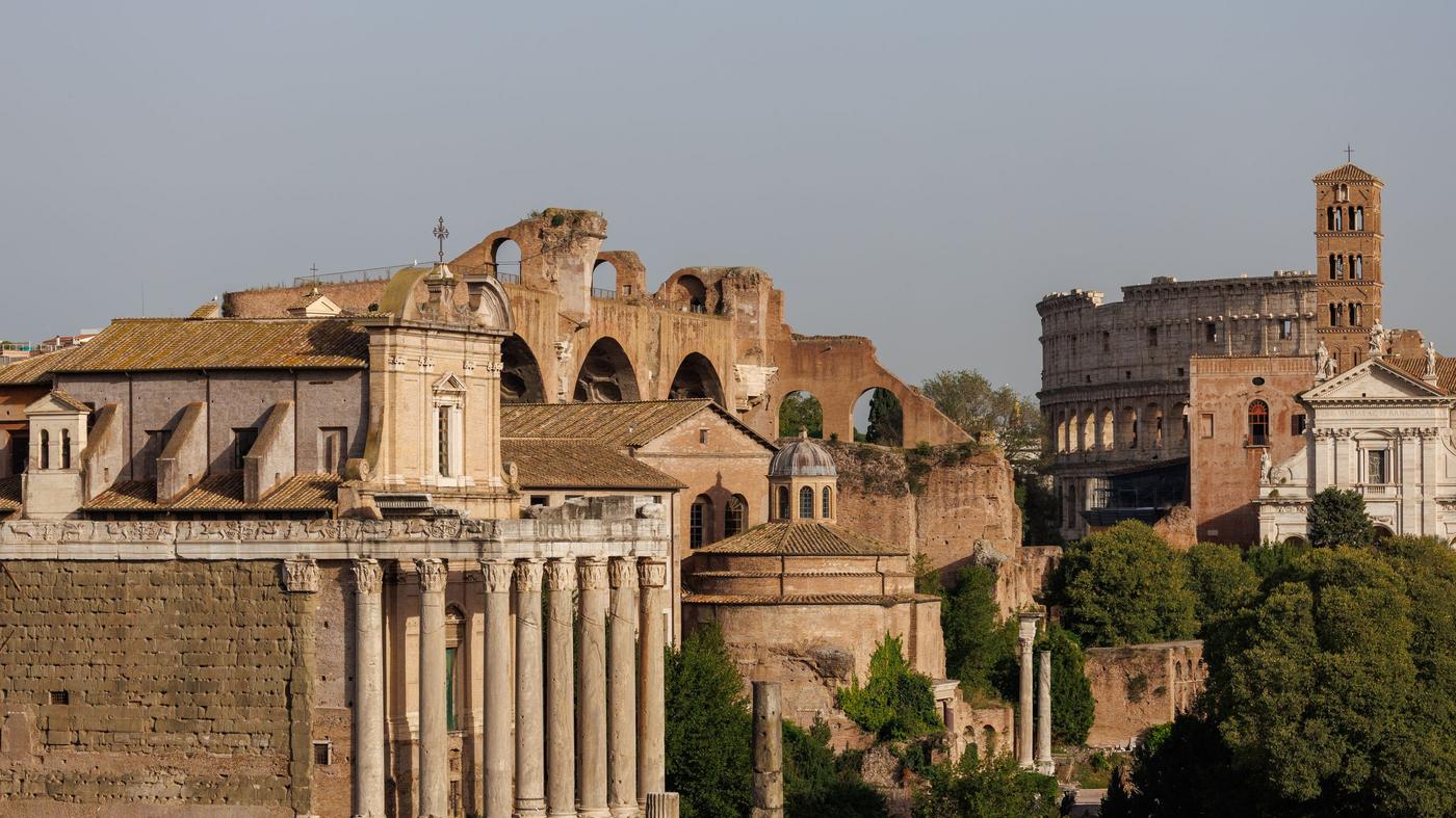 View of the ancient Roman Forum and Colosseum in Rome during sunset.