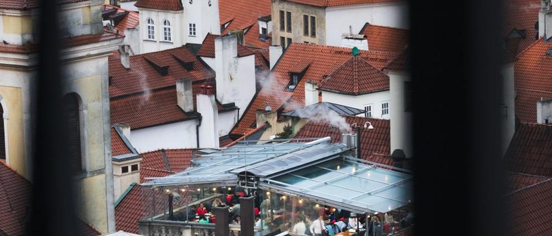 Charming aerial view of Prague's historic rooftops with a bustling café scene below.