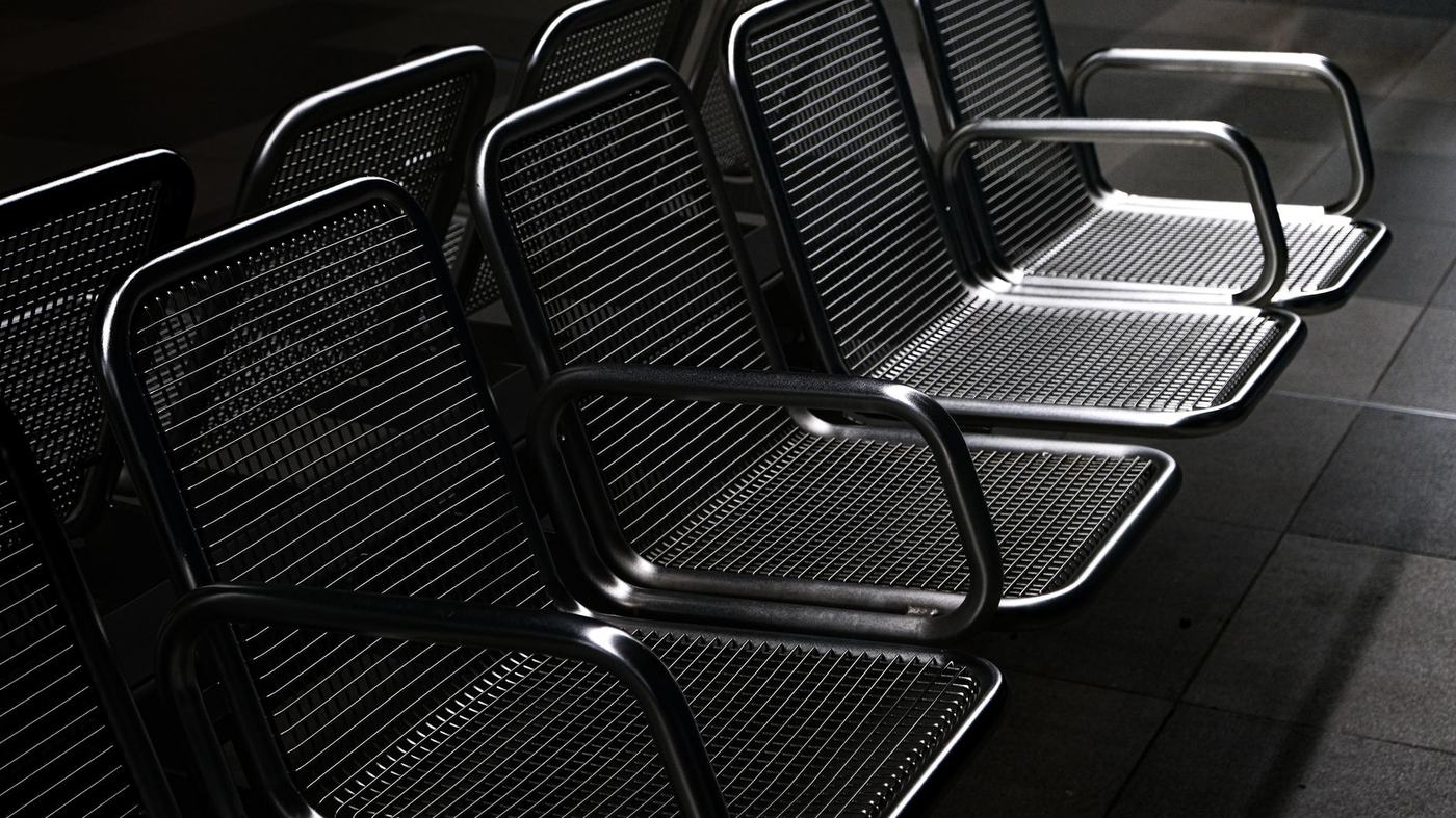 A row of empty metal chairs in a dimly lit terminal, stark and modern.